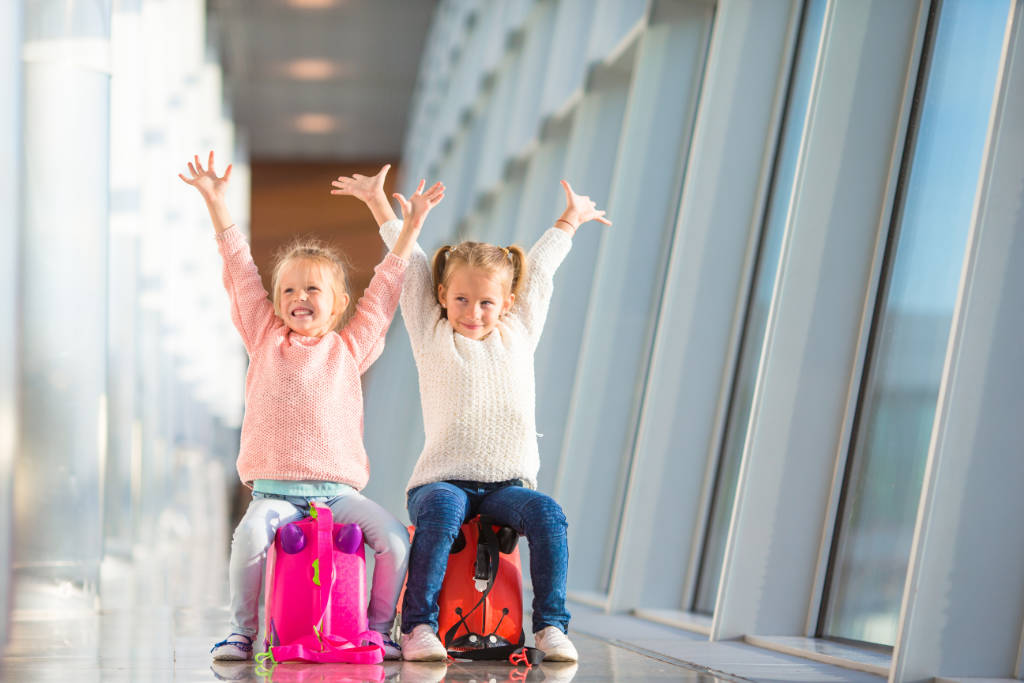 zwei Kinder freuen sich am Flughafen und lachen